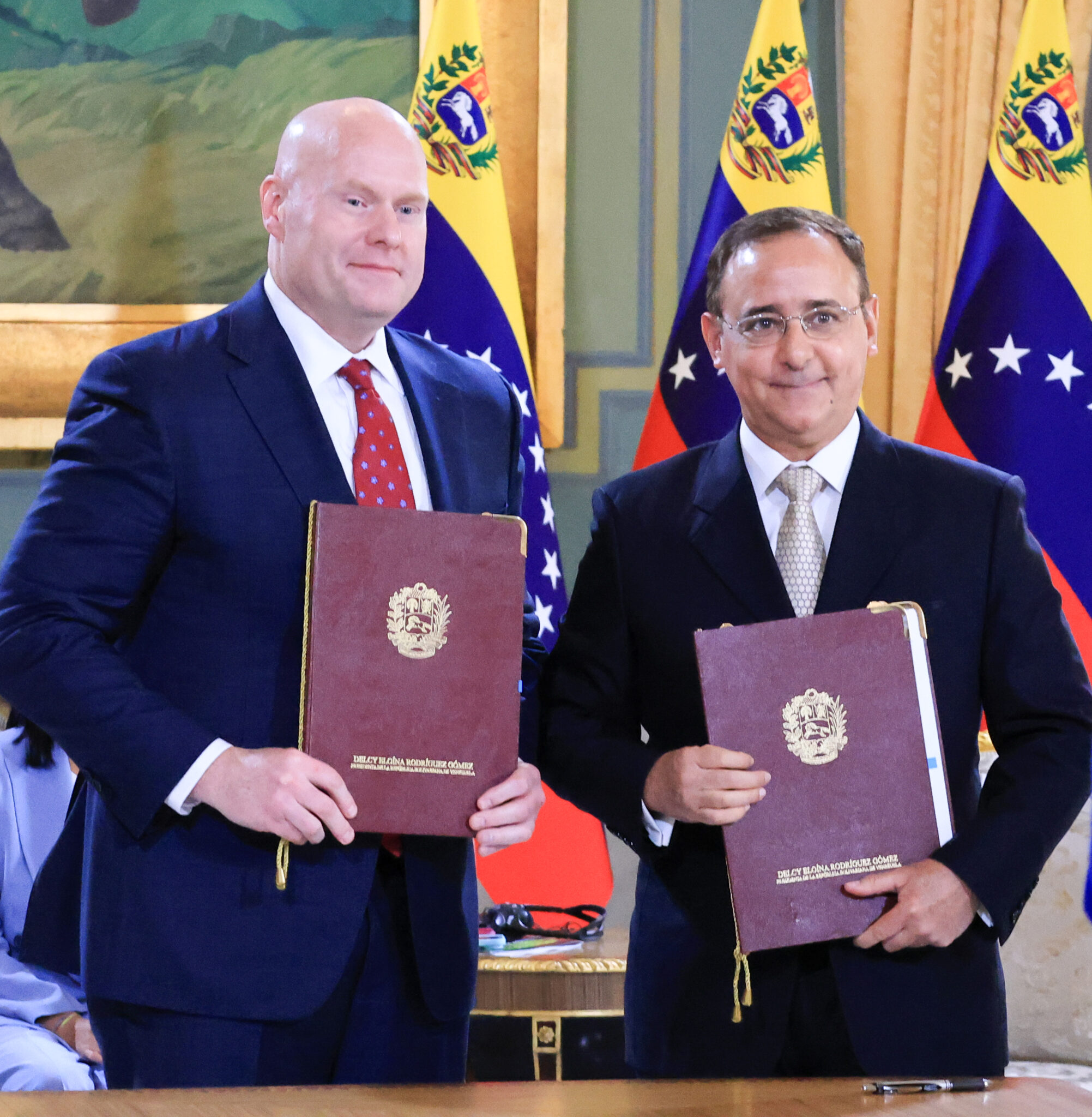 Roger Martella y Eric Gray muestran las carpetas con el Memorando de Entendimiento rubricado